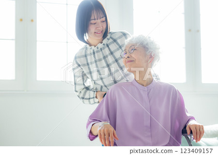 A grandmother in a wheelchair and her granddaughter spending time together in the living room 123409157