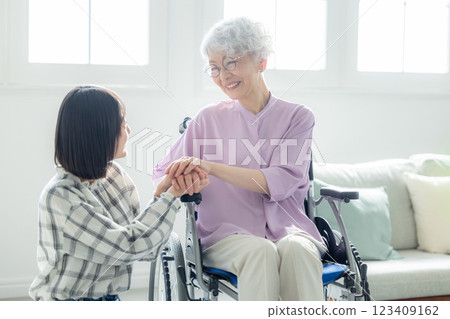 A grandmother in a wheelchair and her granddaughter spending time together in the living room A grandmother in a wheelchair and her granddaughter spending time together in the living room 123409162