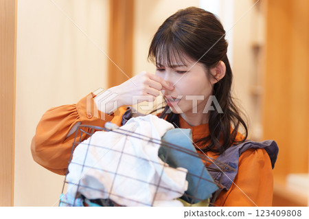 Woman smelling stinky laundry and pinching her nose Woman smelling stinky laundry and pinching her nose 123409808