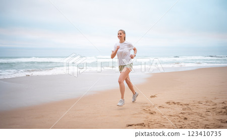 Happy sporty woman jogging on wet seashore against Happy sporty woman jogging on wet seashore against 123410735