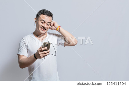 Person listening to music with his cell phone with headphones isolated, Handsome man enjoying music with headphones isolated, cheerful guy listening to music with his cell phone isolated Person listening to music with his cell phone with headphones isolated, Handsome man enjoying music with headphones isolated, cheerful guy listening to music with his cell phone isolated 123411304