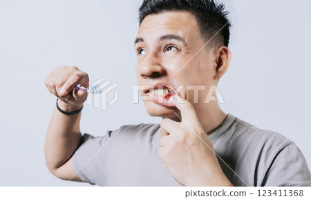 Man holding toothbrush with gum pain isolated, People holding toothbrush with gum problem isolated. Young man with gingivitis holding toothbrush, People holding toothbrush with gum pain 123411368