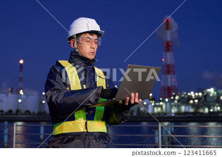 A man wearing a helmet working on a PC outdoors at night A man wearing a helmet working on a PC outdoors at night 123411665