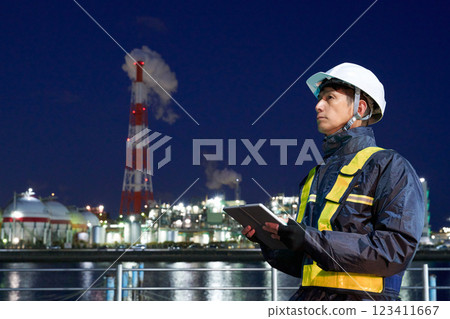 A man wearing a helmet working at a construction site at night A man wearing a helmet working at a construction site at night 123411667