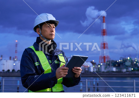 A man wearing a helmet working at a construction site at night A man wearing a helmet working at a construction site at night 123411671