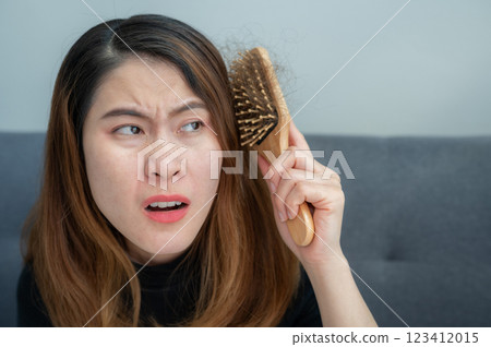 Asian woman having problem of her thick hair while using hair brush. Thick hair weights more than thin hair and prone to damage and frizzy. Asian woman having problem of her thick hair while using hair brush. Thick hair weights more than thin hair and prone to damage and frizzy. 123412015
