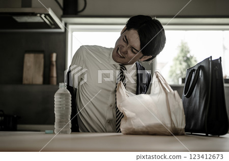 Young Asian businessman getting bored with convenience store bento at home (nutritional balance, diet) 123412673