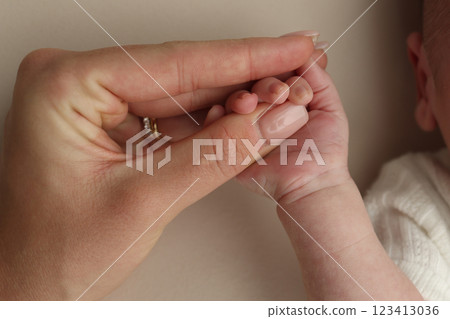 Close-up little hand of child and palm of mother and father. The newborn baby has a firm grip on the parent's finger after birth. A newborn holds on to mom's, dad's finger. Close-up little hand of child and palm of mother and father. The newborn baby has a firm grip on the parent's finger after birth. A newborn holds on to mom's, dad's finger. 123413036