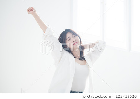 一名女子醒來後,閉上雙眼,伸展身體,沐浴在清晨的陽光,毫無壓力 一名女子醒來後,閉上雙眼,伸展身體,沐浴在清晨的陽光,毫無壓力 123413526