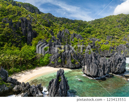 Ocean waves and clear water crashing on limestone rocks and sandy beach. Matinloc Island. El Nido, Philippines. Ocean waves and clear water crashing on limestone rocks and sandy beach. Matinloc Island. El Nido, Philippines. 123413551