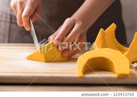 Hand holding kitchen knife and cutting green pumpkin on wooden board, Homemade cooking 123413729