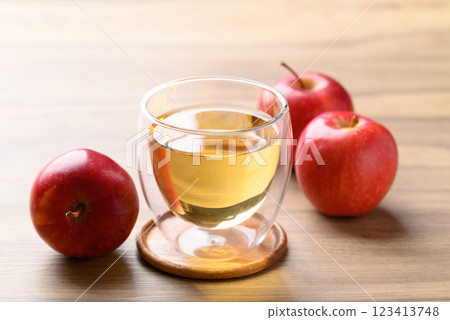 Glass of apple cider and red apple fruit on wooden background 123413748