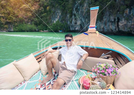 Happy man tourist in private longtail boat trip to koh Hong lagoon island at Krabi, Thailand. landmark, tropical destination, southeast Asia Travel, summer vacation, wanderlust and holiday concept 123414894