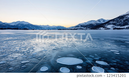 frozen lake with snow covered mountains at sunset creates serene landscape 123415201