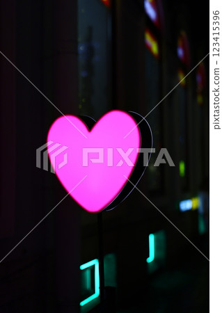 A stunningly vibrant pink heart neon sign captivatingly placed within an urban city environment A stunningly vibrant pink heart neon sign captivatingly placed within an urban city environment 123415396