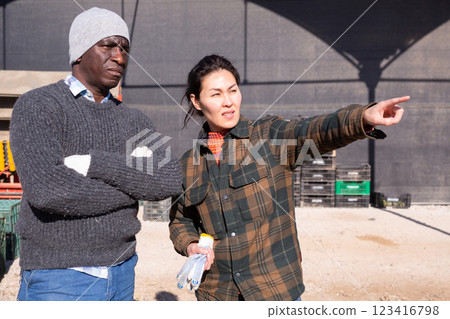 Asian female farmer giving instructions to worker outdoors at farm Asian female farmer giving instructions to worker outdoors at farm 123416798