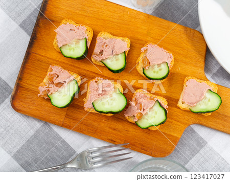 There are sandwiches with pate and cucumber on board 123417027