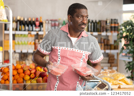 African man in store took raw beef steaks and hamburger cutlet, choose meat ware African man in store took raw beef steaks and hamburger cutlet, choose meat ware 123417052