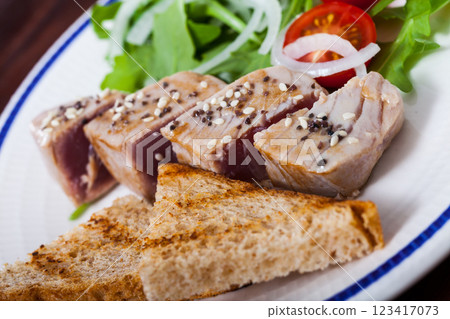 Deliciously lightly fried tuna with toasted bread, served with greens 123417073