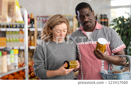African man with European woman make choice choose consider canned pickled olives in store African man with European woman make choice choose consider canned pickled olives in store 123417080