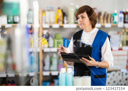 Female manager makes notes on electronic tablet - conducts an inventory in supermarket 123417154