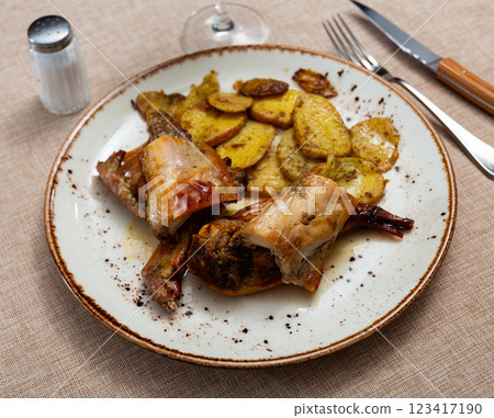 Roasted rabbit pieces with vegetable garnish of fried potatoes 123417190