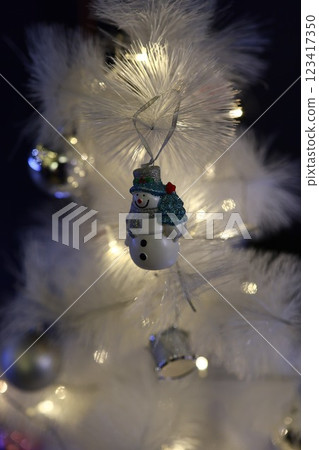 A Festive Snowman Ornament on a White Christmas Tree creates a delightful holiday spectacle 123417350