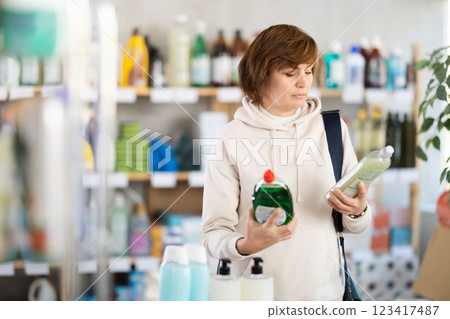 Adult woman chooses dishwashing detergent in store Adult woman chooses dishwashing detergent in store 123417487
