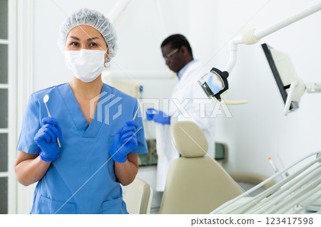 Female dentist standing in dental office with tools in hands Female dentist standing in dental office with tools in hands 123417598