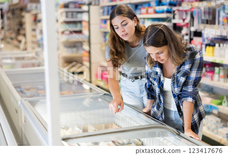 Two female friends choose frozen food at grocery store 123417676