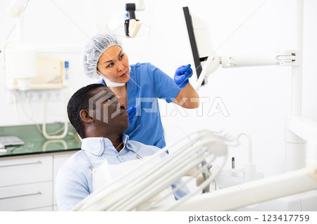 Woman dentist pointing at display to show information to patient Woman dentist pointing at display to show information to patient 123417759