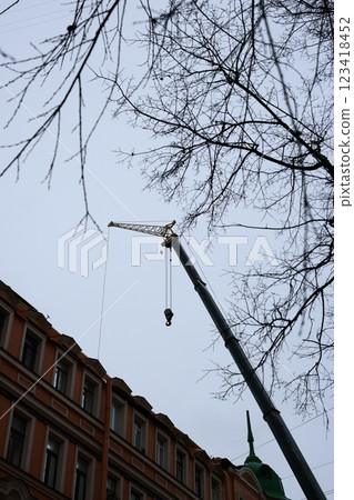 A construction crane operates overhead in an urban area filled with buildings and infrastructure A construction crane operates overhead in an urban area filled with buildings and infrastructure 123418452