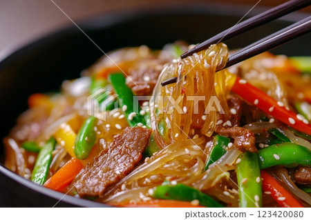 A close-up view of Japchae glass noodles served with colorful vegetables and tender beef A close-up view of Japchae glass noodles served with colorful vegetables and tender beef 123420080