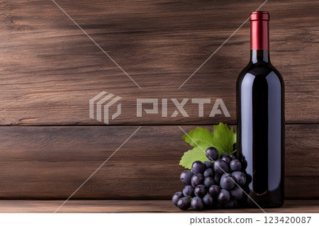 A dark glass bottle of red wine placed next to fresh grapes against a rustic wooden background A dark glass bottle of red wine placed next to fresh grapes against a rustic wooden background 123420087