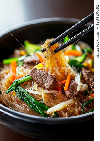A close-up view of Japchae glass noodles garnished with vegetables and beef served in a bowl 123420092