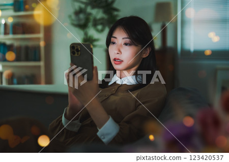 A woman at night staring at her smartphone A woman at night staring at her smartphone 123420537