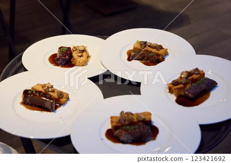 Savor gourmet dishes artfully presented on white plates at an exquisite dining event 123421692