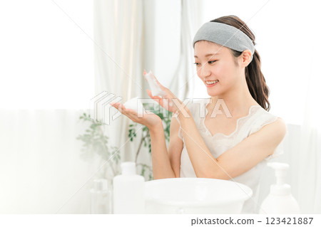 Young Asian woman washing her face with facial cleansing foam/facial cleanser at home Young Asian woman washing her face with facial cleansing foam/facial cleanser at home 123421887