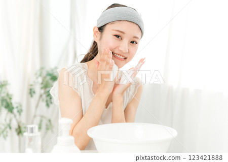 Young Asian woman washing her face with facial cleansing foam/facial cleanser at home Young Asian woman washing her face with facial cleansing foam/facial cleanser at home 123421888