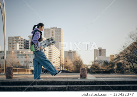 一名女子帶著滑板穿過公園 一名女子帶著滑板穿過公園 123422377