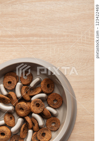 Dry dog food in a slow feeder bowl placed on a wooden surface Dry dog food in a slow feeder bowl placed on a wooden surface 123422469