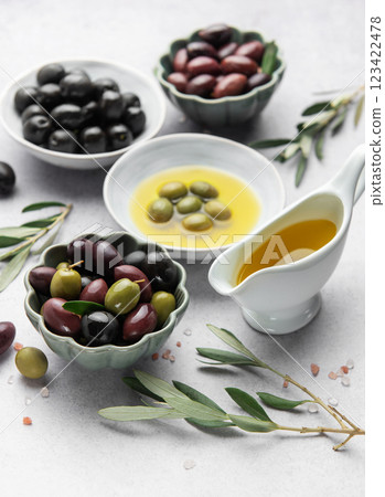Bowls of various olives with olive oil and olive branches on marble table 123422478