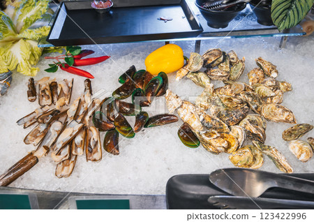 Asian seafood in buffet at hotel restaurant in Asia. Fresh oysters and mussels sea clams on ice at a night market in Vietnam Asian seafood in buffet at hotel restaurant in Asia. Fresh oysters and mussels sea clams on ice at a night market in Vietnam 123422996