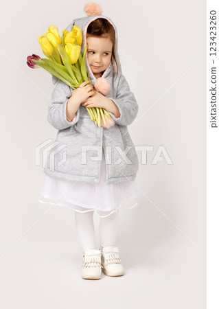 Thoughtful Toddler in Bunny Costume Holding a Bouquet of Yellow and Burgundy Tulips 123423260