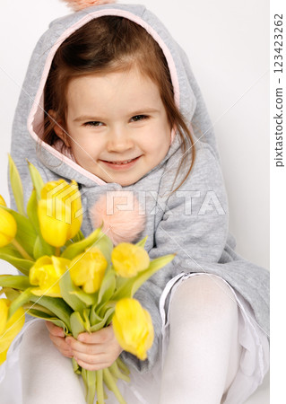 Smiling Toddler in Bunny Costume Holding Yellow Tulips on White Grey Background 123423262