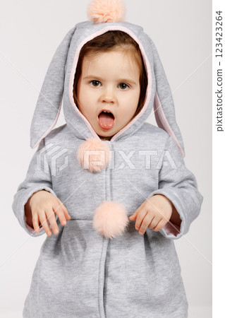 Playful Toddler in Bunny Costume Making a Funny Face on White Background 123423264