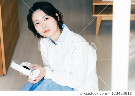 Woman with headphones by the window Woman with headphones by the window 123423918