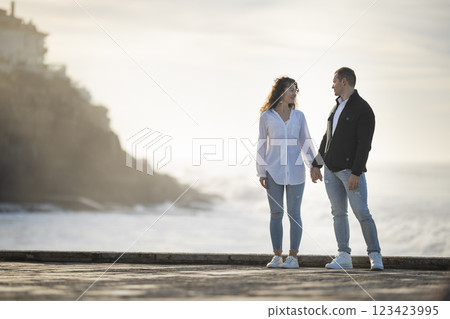 Young couple holding hands at the beach during golden hour 123423995