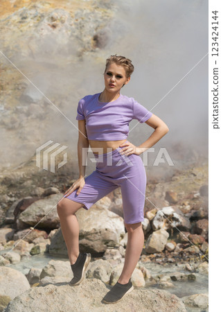 Slender trainer standing on rock in steaming geyser in crater active volcano during summer workout 123424144