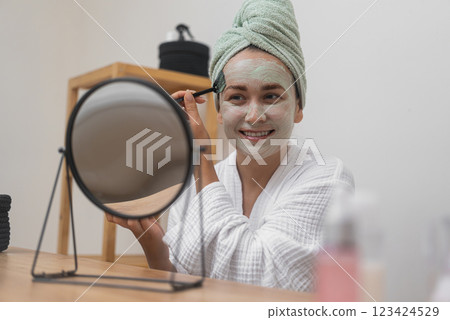 Beauty Ritual: Draped in a towel, she indulges in a post-bath facial mask, targeting anti-aging, hydration, and skin perfection.  123424529